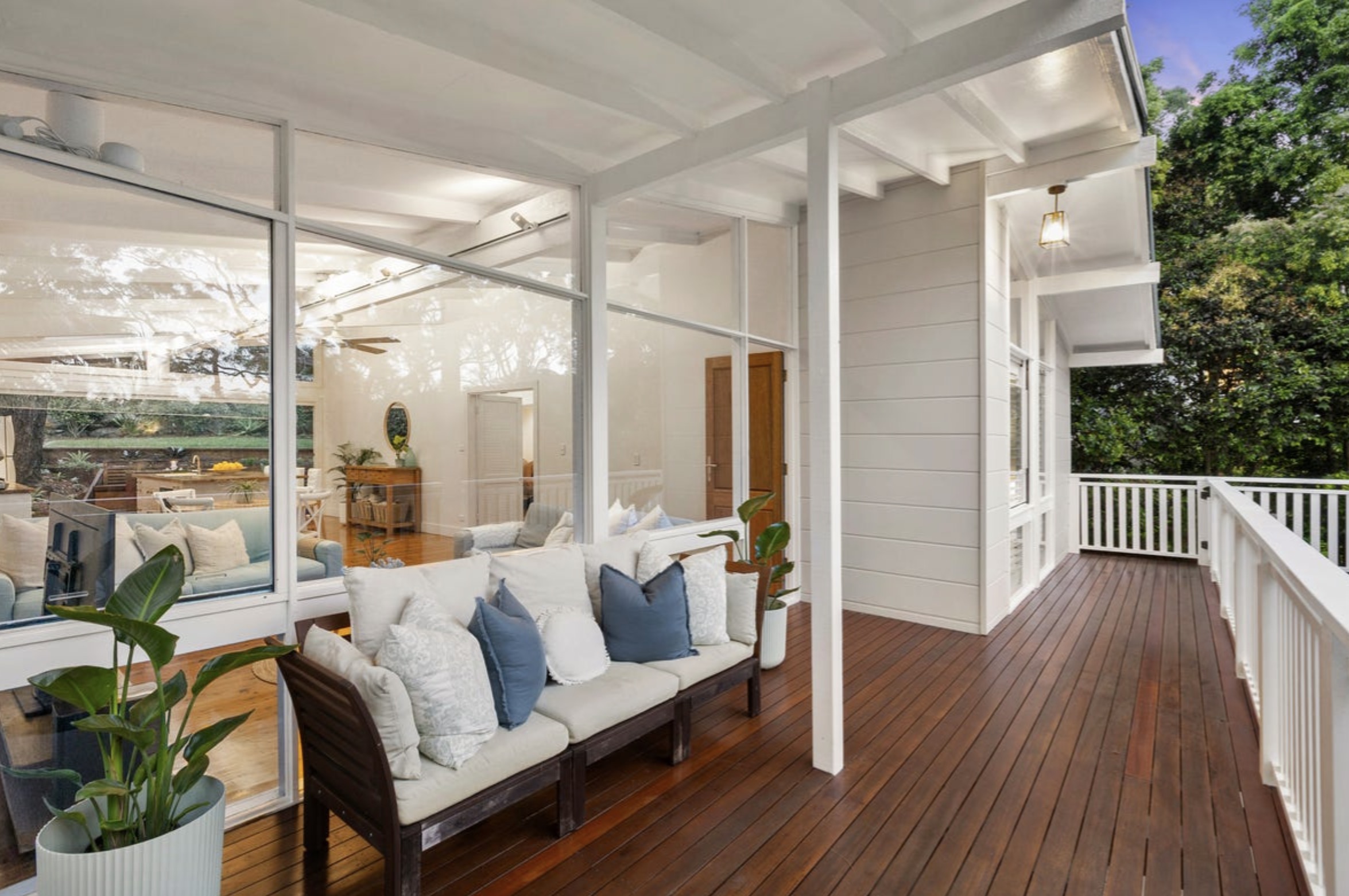 Heritage deck with cushioned sofa and plants outside large-windowed home by Buyers Agent seaforth.