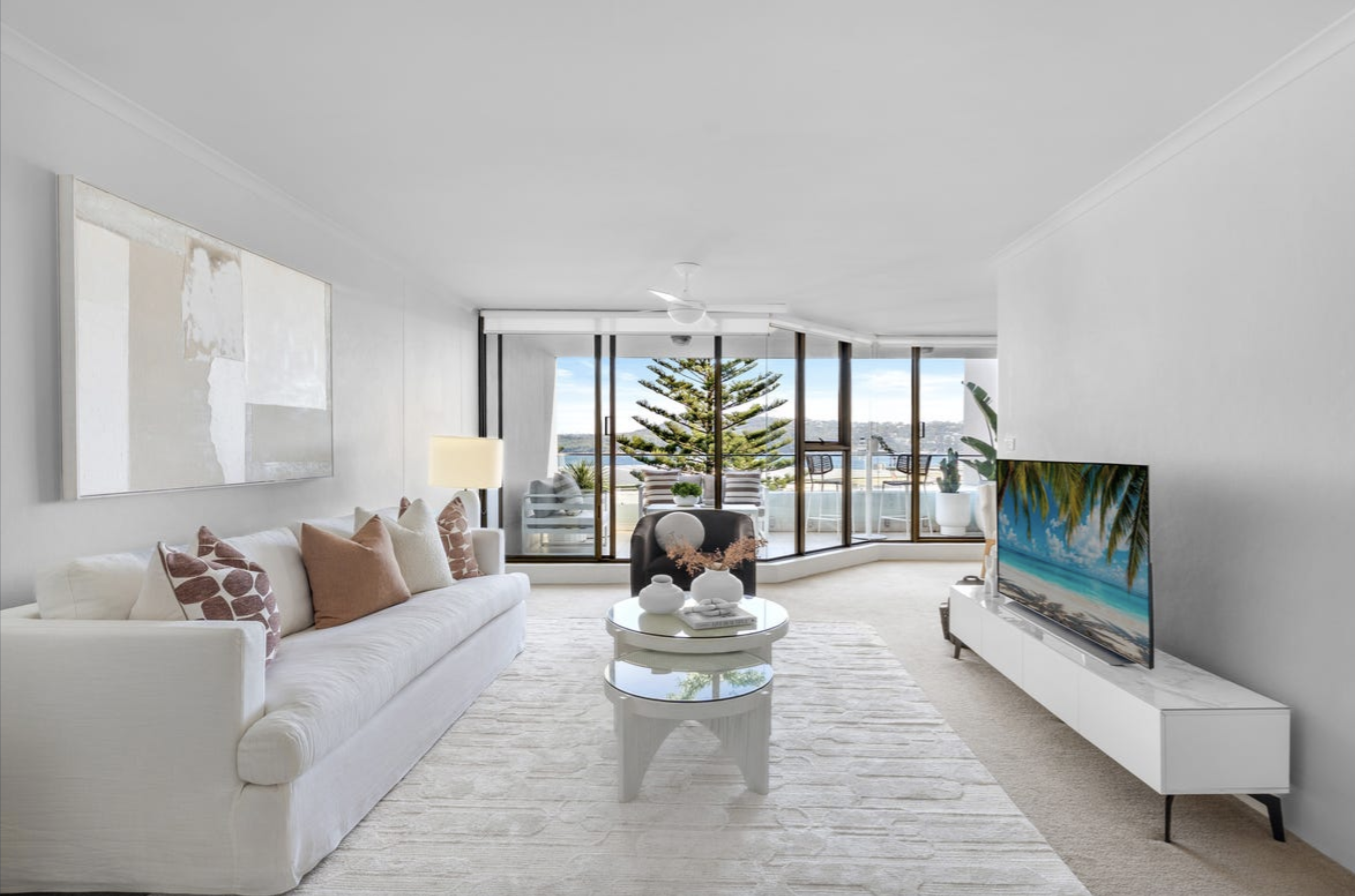 Bright living room with white sofa and large windows showing an ocean view.
