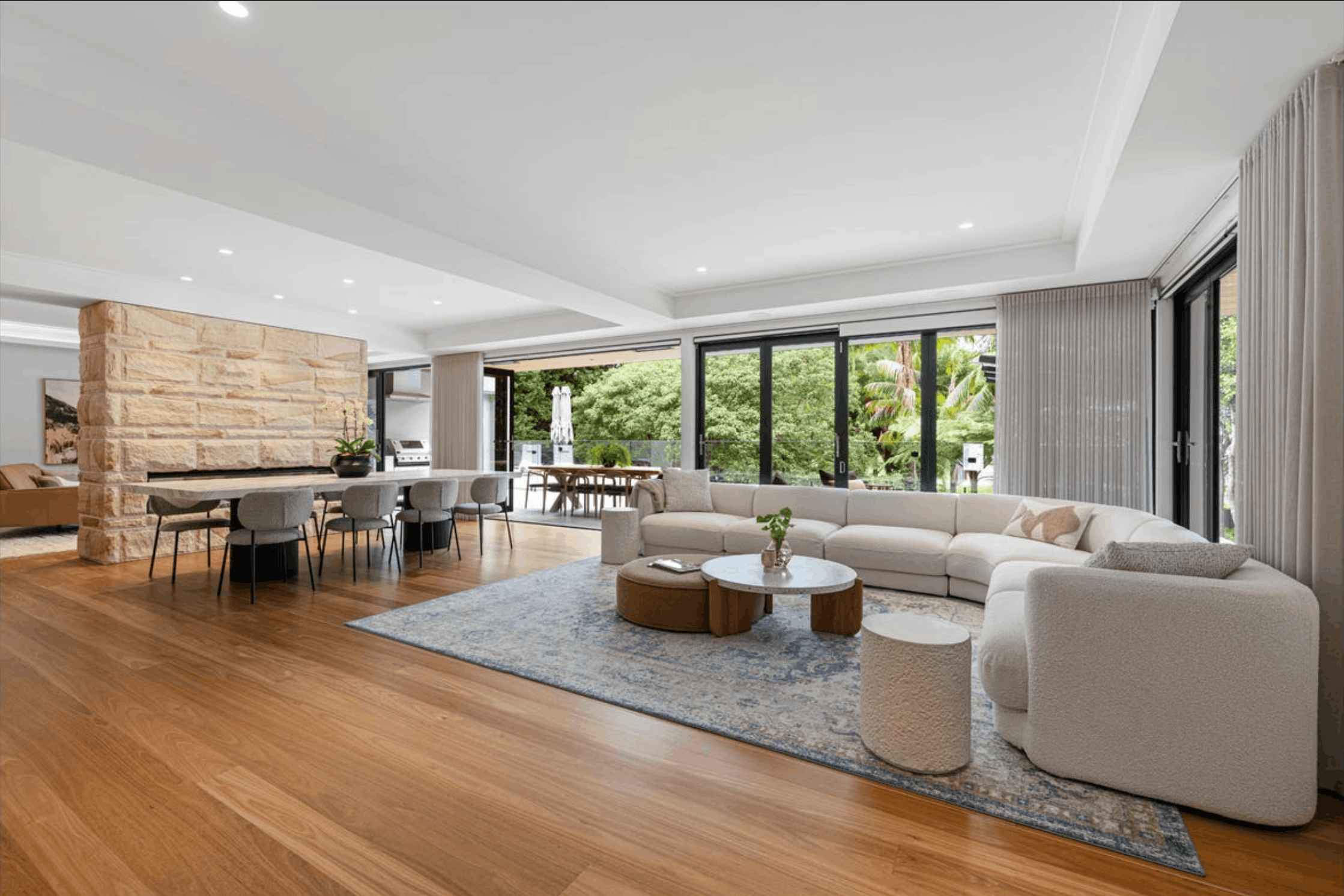 Modern open-plan living and dining area with pest inspection in northern beaches, light wood flooring, sectional sofa, and large windows.